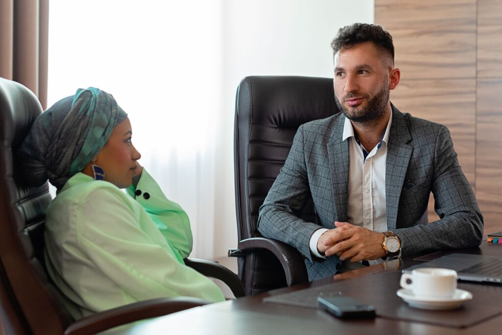 two professionals in a business meeting discussing a project at an office desk.