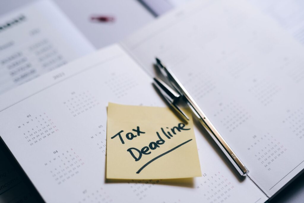 a close-up of a calendar with a sticky note reminding about the tax deadline.