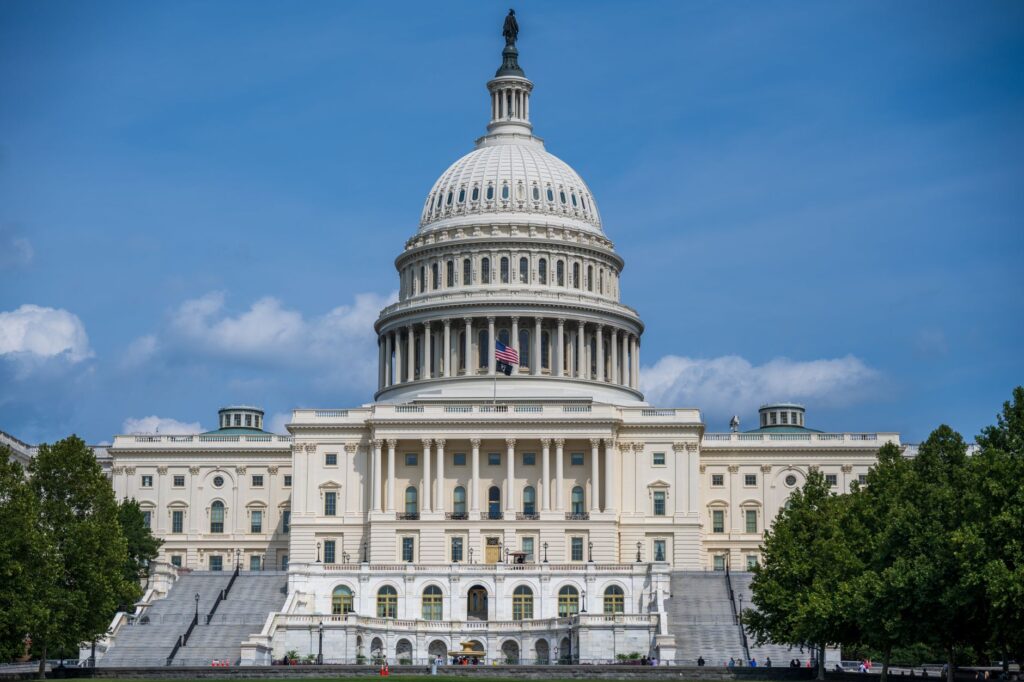 a frontal view of the iconic us capitol building in washington d.c. under blue skies.
