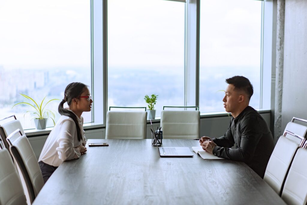 two professionals engaged in a business meeting in a modern office with city views.