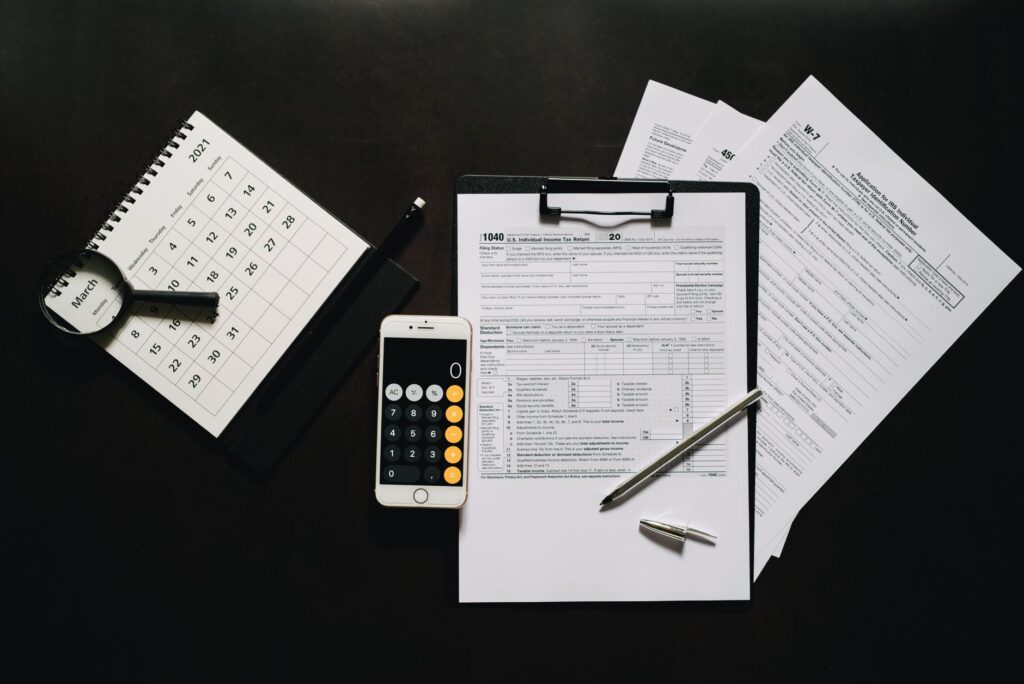 flat lay of financial tools for tax preparation including forms, calculator, and calendar.