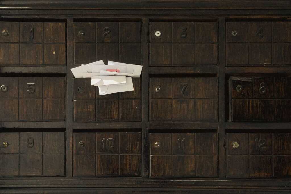 old wooden mailbox showing numbered slots and inserted letters.