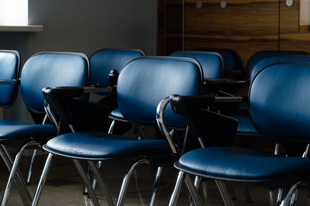 a row of blue desk chairs in a quiet, dimly lit room, ready for use.