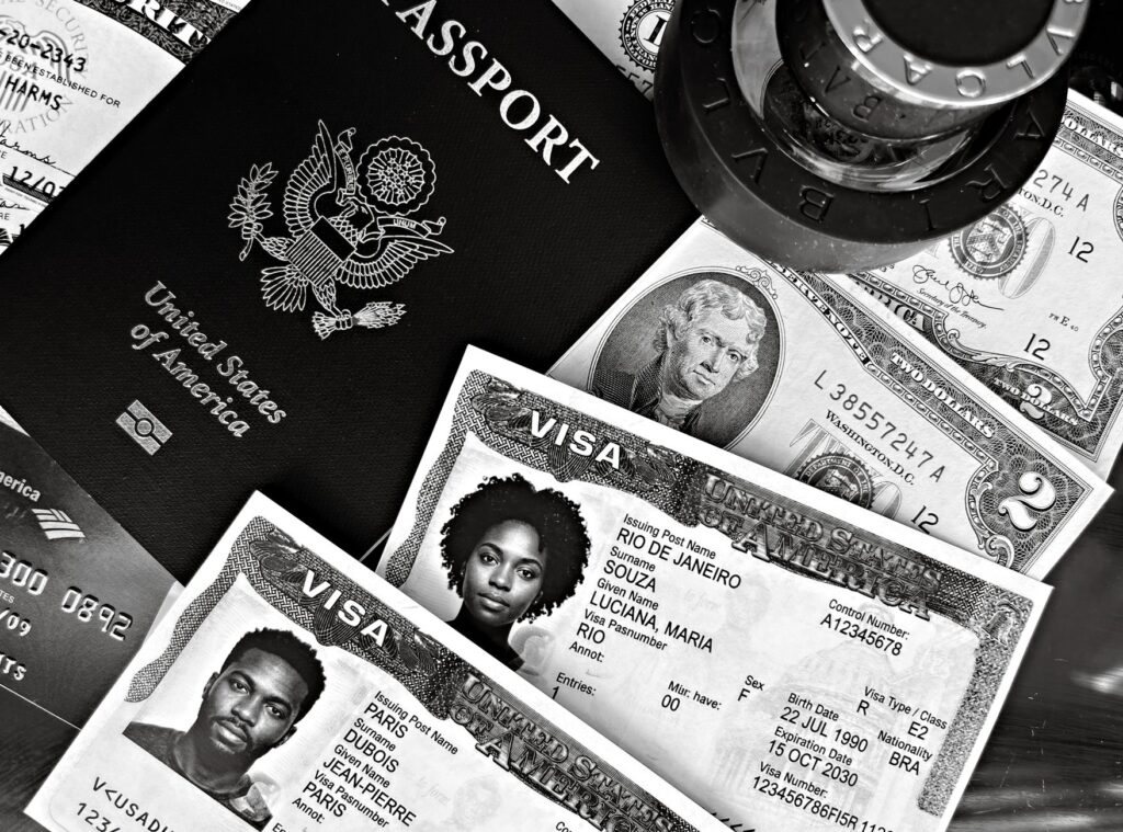 a black and white composition of a us passport, visas, and currency, showcasing travel essentials.
