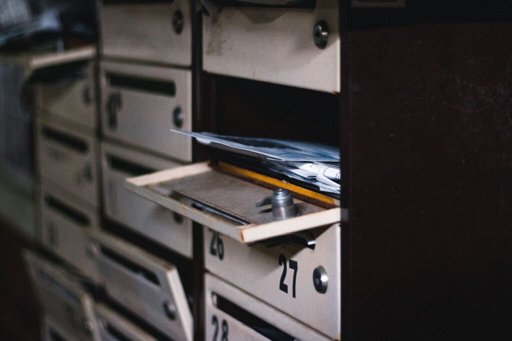 close-up of an open mailbox in a residential building with visible mail, showcasing selective focus.