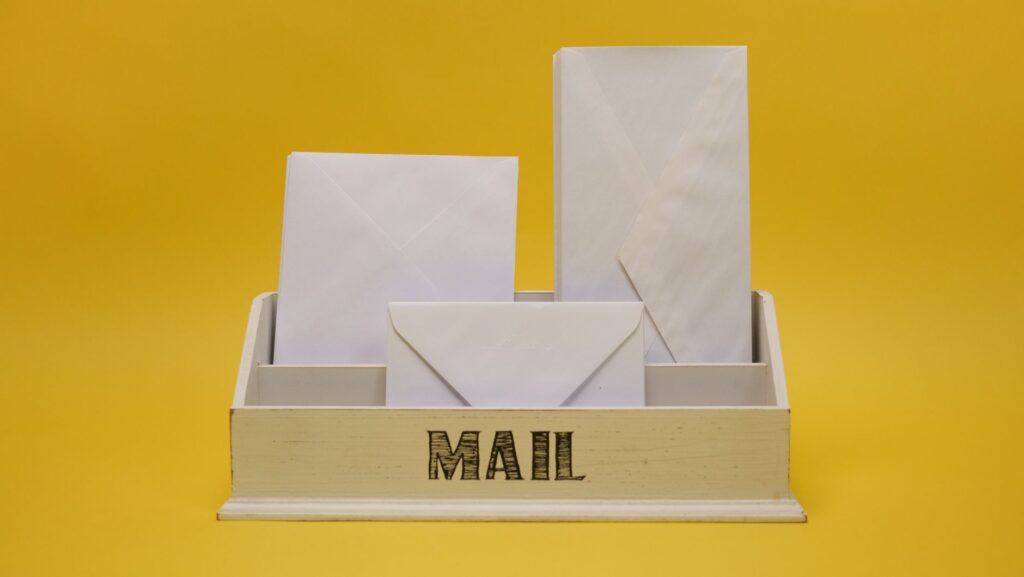 white envelopes neatly arranged in a mail organizer against a vibrant yellow background.
