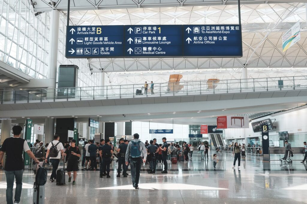 crowded scene inside hong kong international airport terminal with travelers and signage.
