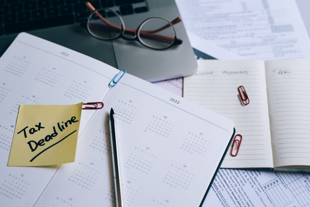 a desk with a planner, sticky note marked 'tax deadline', and paperwork, indicating financial planning.