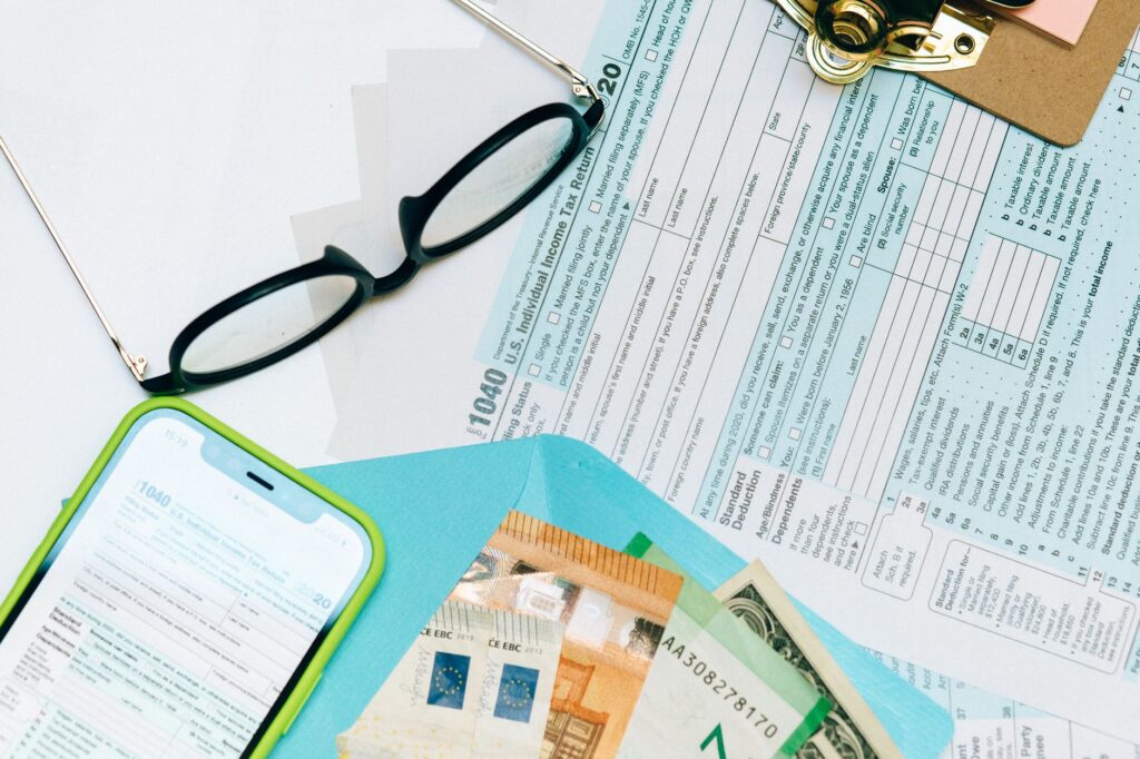 close-up of tax forms, smartphone, and dollar bills for financial analysis and preparation.
