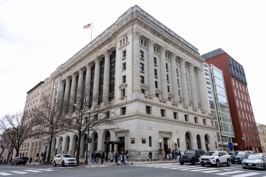 street view of an iconic historic building in washington d.c. with cars and pedestrians on a sunny day.