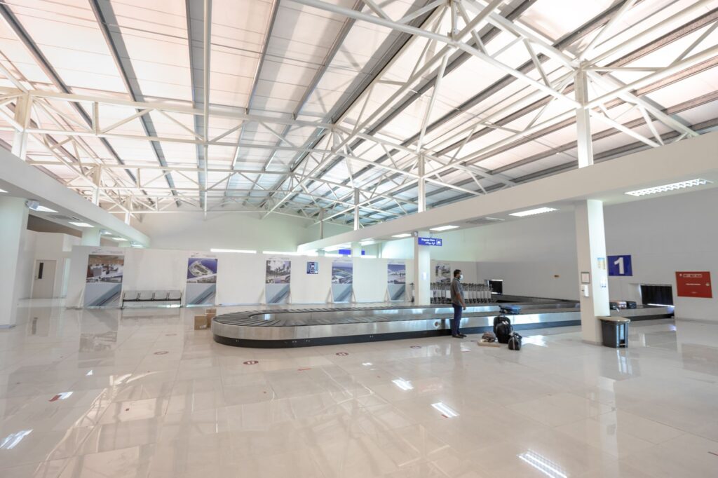 a modern and empty airport baggage claim area with a traveler waiting.