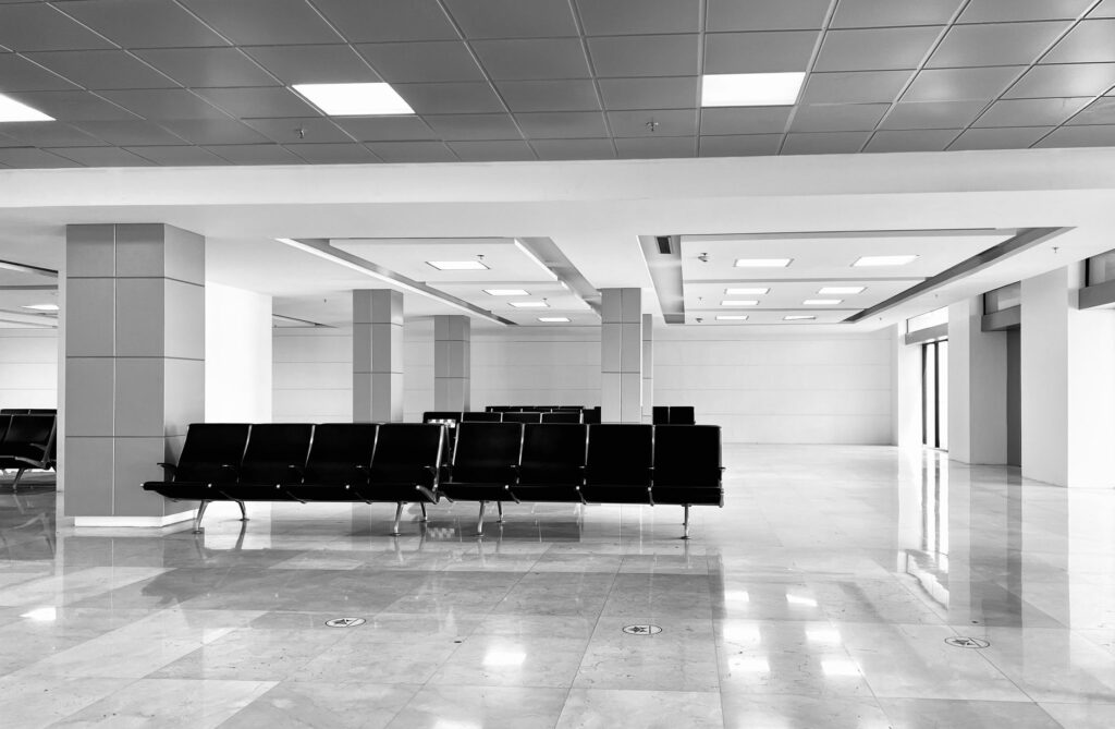 black chairs in a spacious, minimalist waiting area with white tiles and bright lighting.